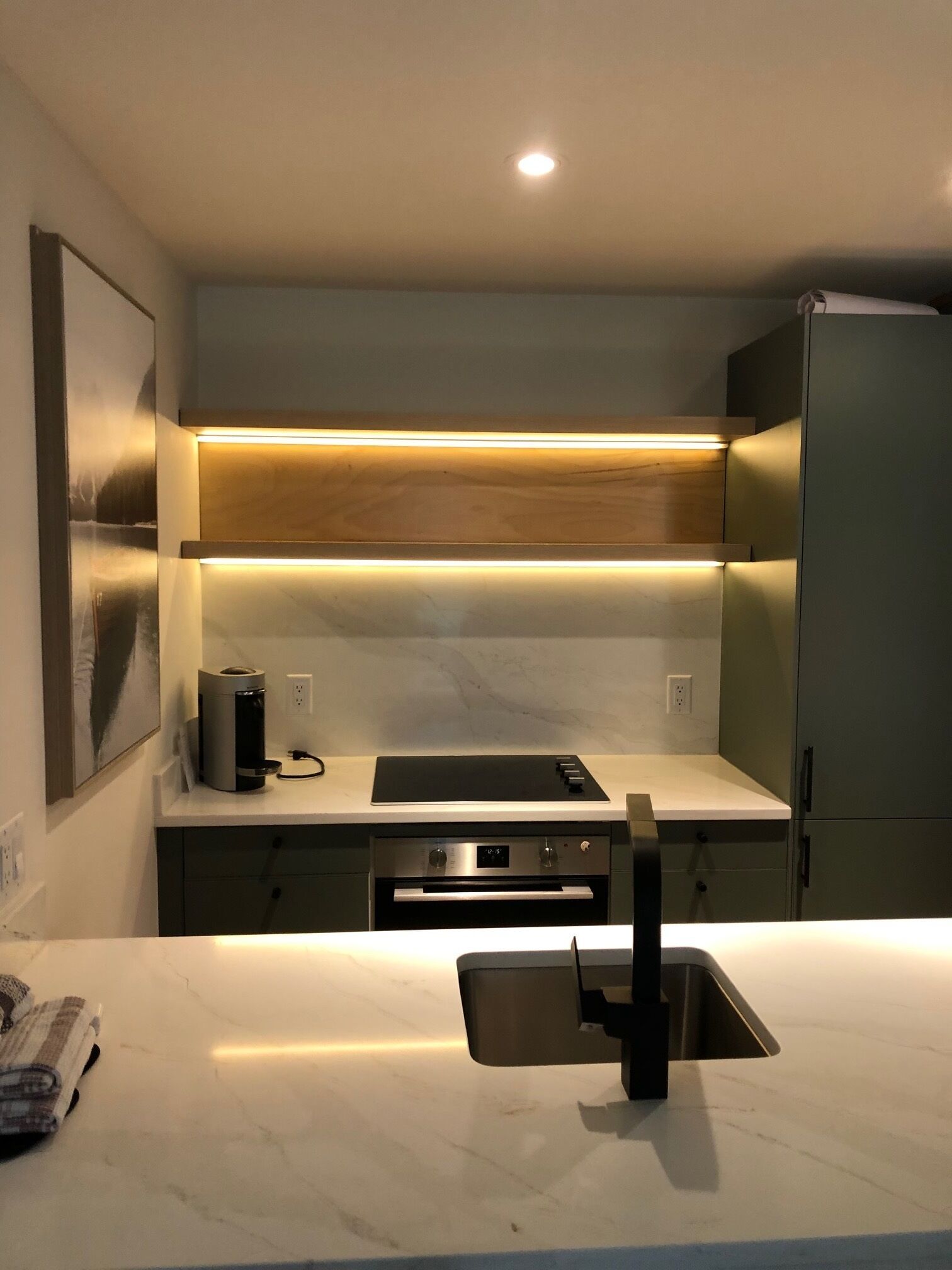 Una cocina moderna con horno integrado, cafetera y pileta de acero inoxidable.