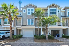A multi-story residential building with a garage, a driveway, and palm trees. - ⛱️Heated Community Pool-Gorgeous 4BR Townhome-Walk to beach-Emerald Escape⛱️ (Miramar Beach)