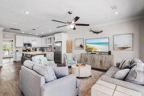 A modern kitchen with white cabinets, a dining area with a wooden table, a gray sofa set, and a ceiling fan. - ⛱️Heated Community Pool-Gorgeous 4BR Townhome-Walk to beach-Emerald Escape⛱️ (Miramar Beach)