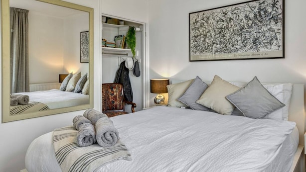 Une chambre d’hôtel avec un grand lit, un miroir, une armoire et une œuvre d’art encadrée au mur.