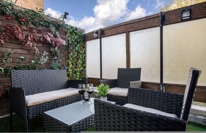 Ein Außenbereich mit Korbmöbeln, einem Tisch und einem Blumentopf.