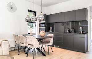 A modern kitchen with dark cabinets, a dining table with chairs, and pendant lights. - Awesome home in Wenum-Wiesel with WiFi (Wenum-Wiesel)