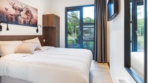 Une chambre d’hôtel moderne avec un grand lit, un téléviseur fixé au mur et une vue sur l’extérieur.