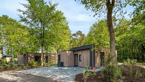 Eine moderne Holzhütte mit Schotterauffahrt, umgeben von dichtem Wald.