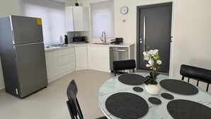 Eine moderne Küche mit Kühlschrank, Spüle und Essbereich mit einem Glastisch und Stühlen.