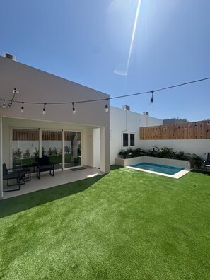 A modern house with a swimming pool, outdoor seating, and string lights. - Orquidea Apt 1- NEW 2 bdr-2bth with pool-perfect retreat (Washington)