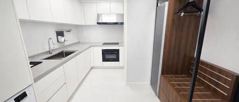 A modern kitchen with white cabinets, a built-in oven, and a wooden pantry.