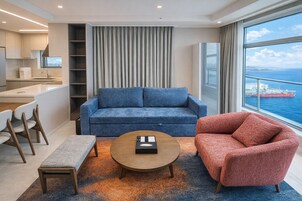 Una sala de estar moderna con un sofá, un sillón, una mesa de centro y vista al mar.