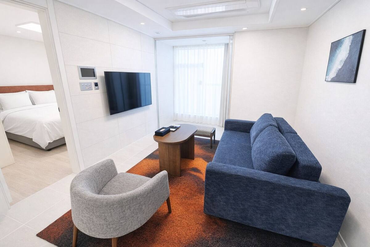 A hotel room with a bed, a TV, a sofa, a chair, and a coffee table.