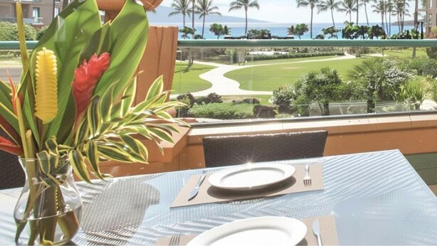 Una mesa de comedor con vista a un jardín ajardinado y una playa.