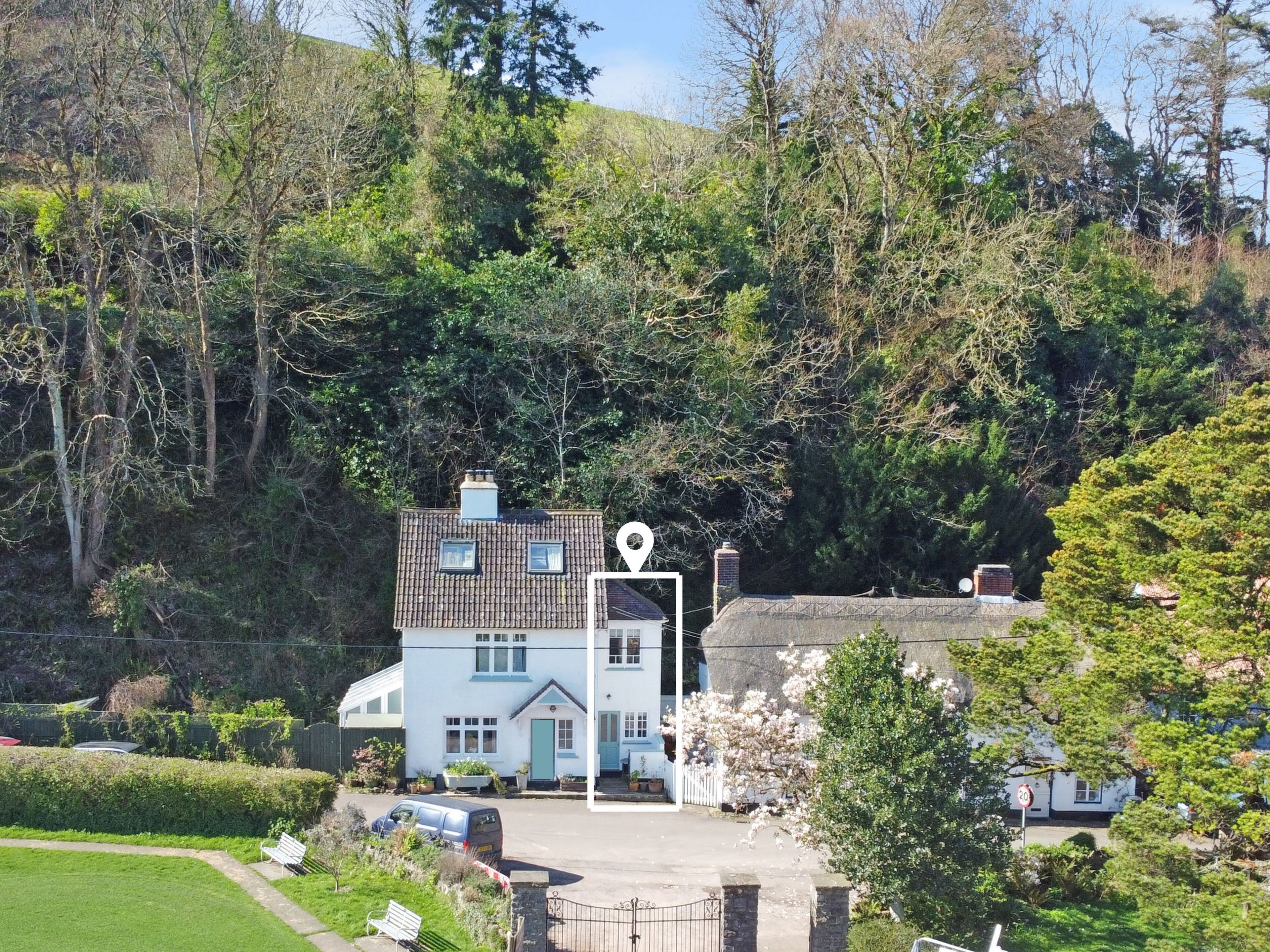 A two-story house with a garden, a driveway, and a white fence.