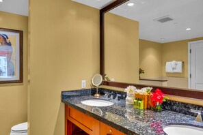Un baño con lavamanos doble, un espejo grande y un cuadro en la pared.