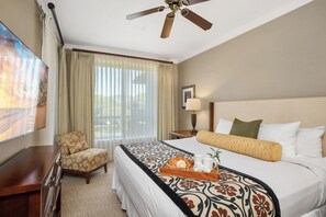 A hotel room with a bed, a TV, a ceiling fan, a chair, a nightstand, and a window with curtains. - 2 Honua Kai Villas | Ocean View | Sleeps 10 | Free Car w/ 6+ Nights | ML-3281 (Lahaina)