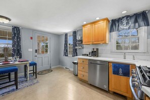 Una cocina compacta con armarios de madera, lavavajillas de acero inoxidable y estufa.