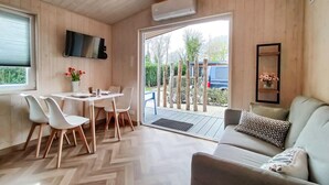 A modern interior with a dining area, a sofa, and a TV mounted on the wall. - 2 bedroom lovely home in Heinkenszand (Heinkenszand)