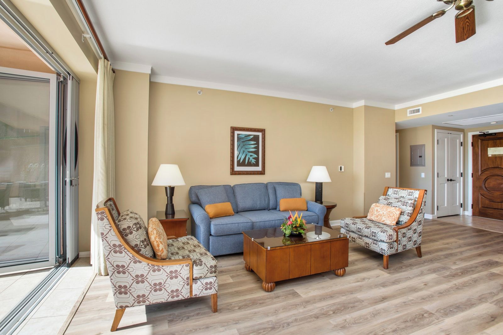 Una sala de estar con un sofá, dos sillones, una mesita de centro y un ventilador de techo.