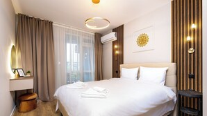 A hotel room with a large bed, a bedside table with a lamp, a wall-mounted air conditioner, and a window with curtains. - A2 Modern 1-bed Apartment 1 (Plovdiv)