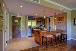 A kitchen with a central island, wooden cabinets, a refrigerator, and a microwave. - Honua Kai | Ocean View 4 BR, Sleeps 12 | Car Incl. w/ 6+ Nights | HKK ML-3305 by KBM (Lahaina)