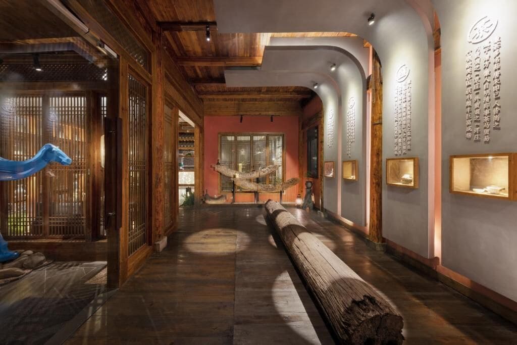Un intérieur traditionnel avec des poutres en bois, un banc central en bois et des présentoirs fixés au mur.