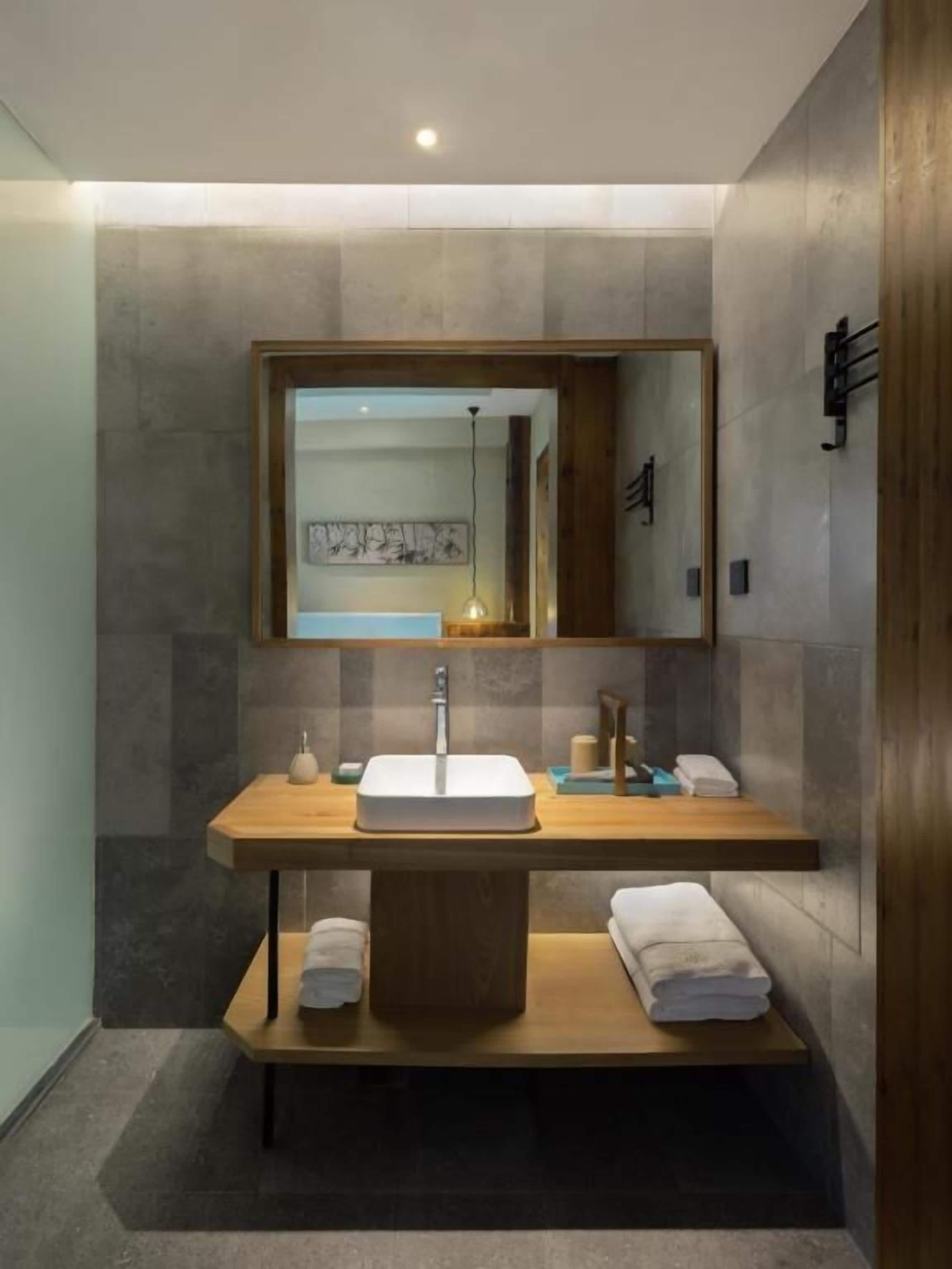 Une salle de bain moderne avec un grand miroir, un meuble-lavabo en bois et un lavabo encastré.