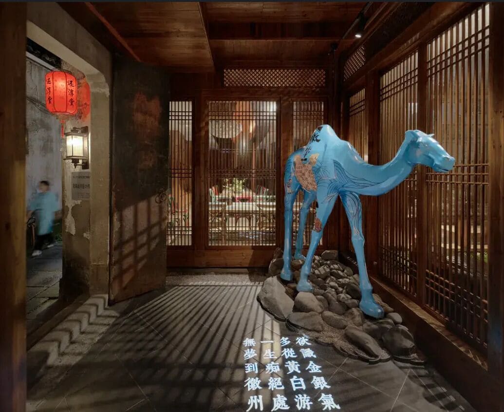 A corridor with a blue camel sculpture, wooden doors, and a patterned floor.