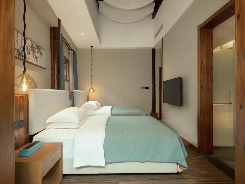 A modern bedroom with a bed, bedside tables, a TV, and a wooden door.