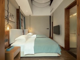 A modern bedroom with a bed, bedside tables, a TV, and a wooden door.
