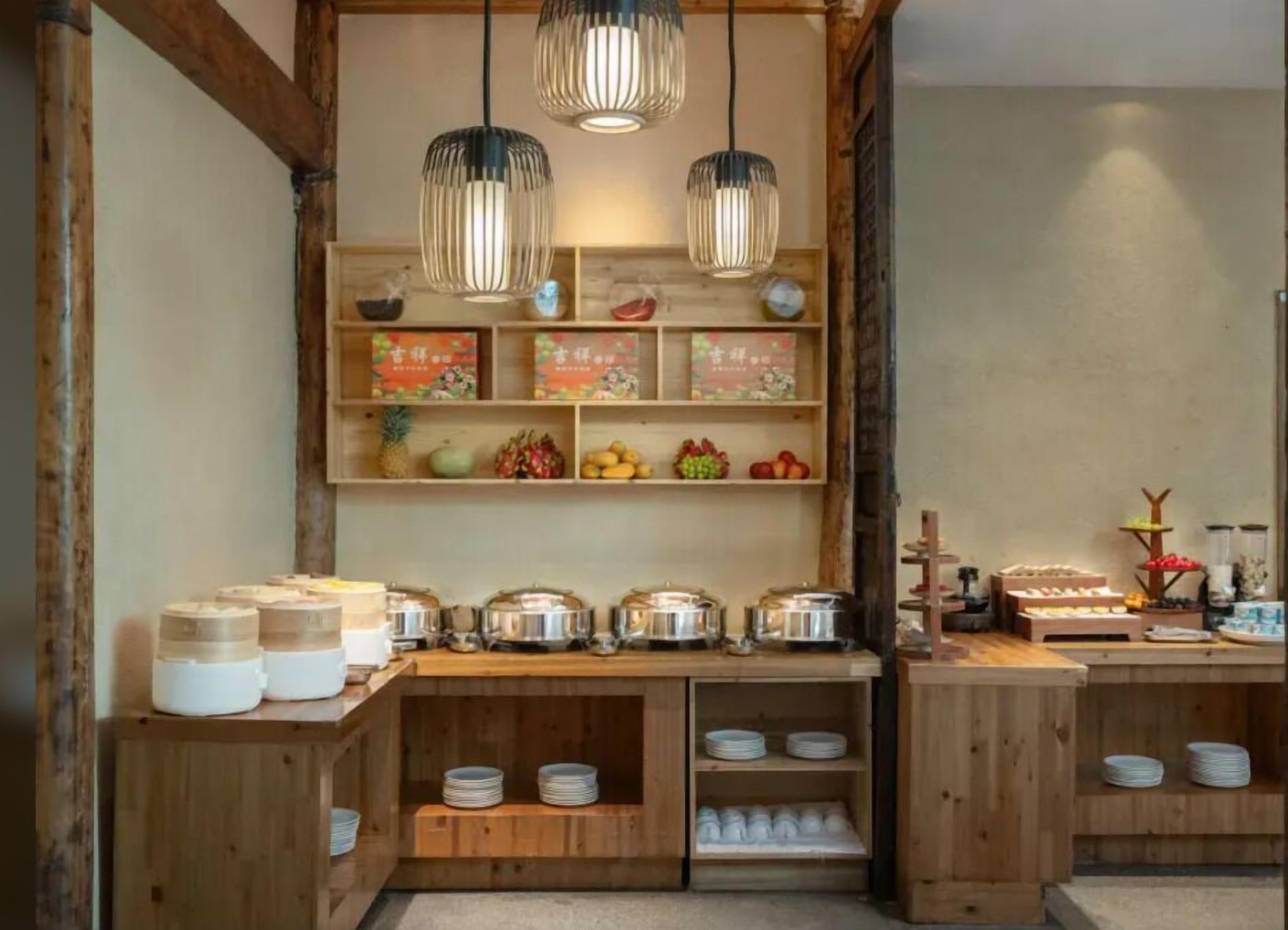 A wooden buffet setup with shelves of food items and hanging pendant lights.