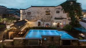 A historic building with a swimming pool, stone walls, and traditional architecture.