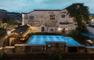 A historic building with a swimming pool, stone walls, and traditional architecture.