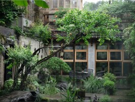 Un patio tradicional con un árbol, un farol de piedra y un edificio con grandes ventanales.