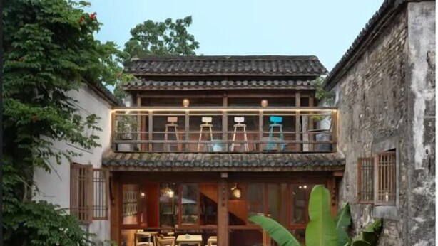A traditional building with a balcony, a dining area, and a small garden with a water feature.