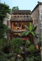Un edificio tradicional con balcón, zona de comedor y un pequeño jardín con fuente.