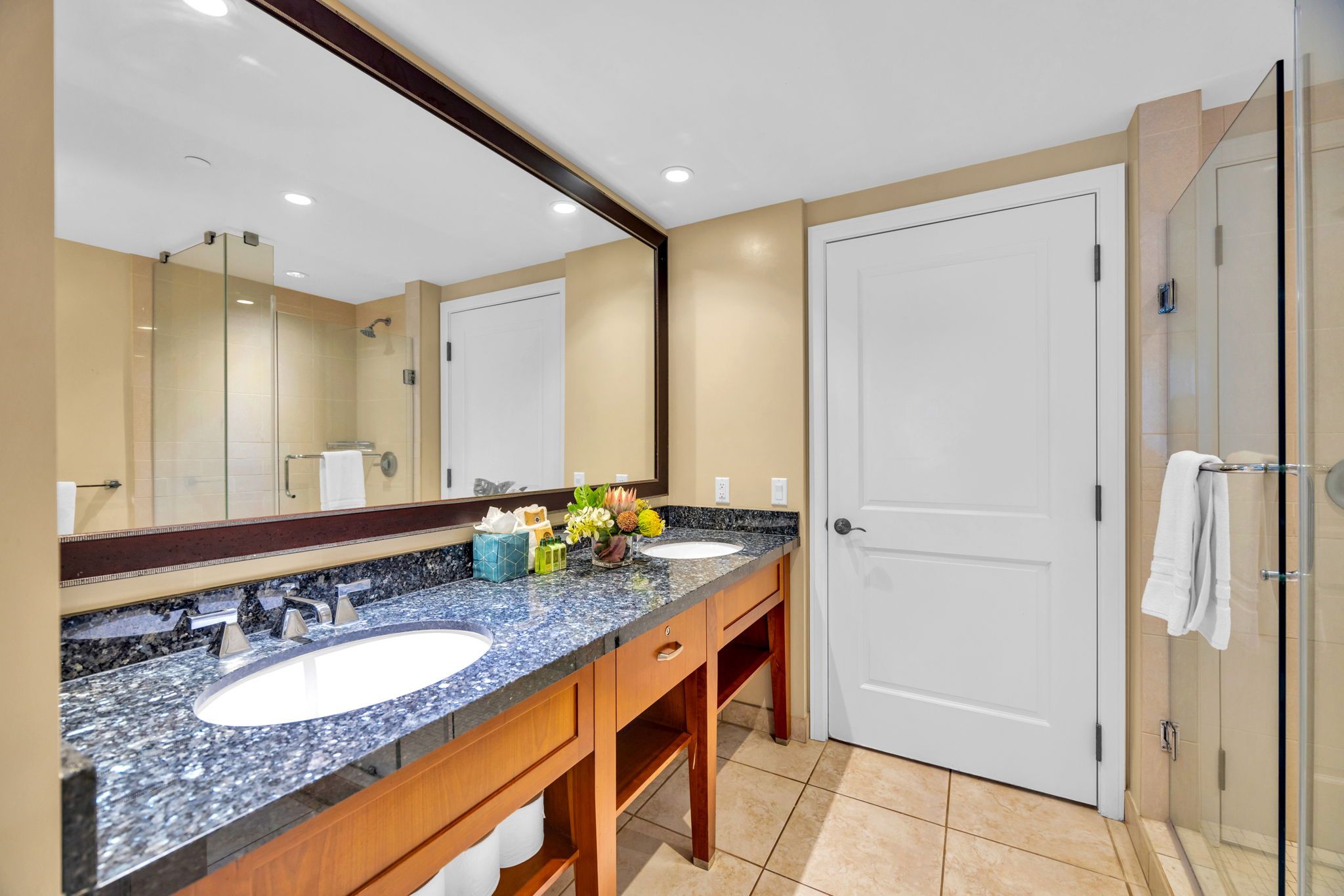 A bathroom with two sinks, a large mirror, and a glass shower enclosure.