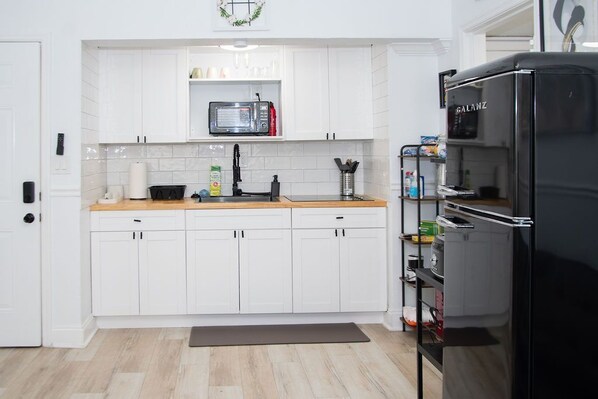 A modern kitchen with white cabinets, a black refrigerator, and a microwave on the countertop.