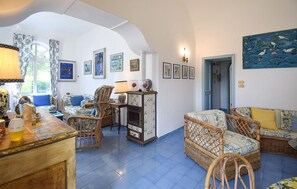 A living room with wicker furniture, a tiled floor, and wall-mounted artwork.