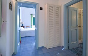 A hallway with a bed, a closet, and a door leading to another room.