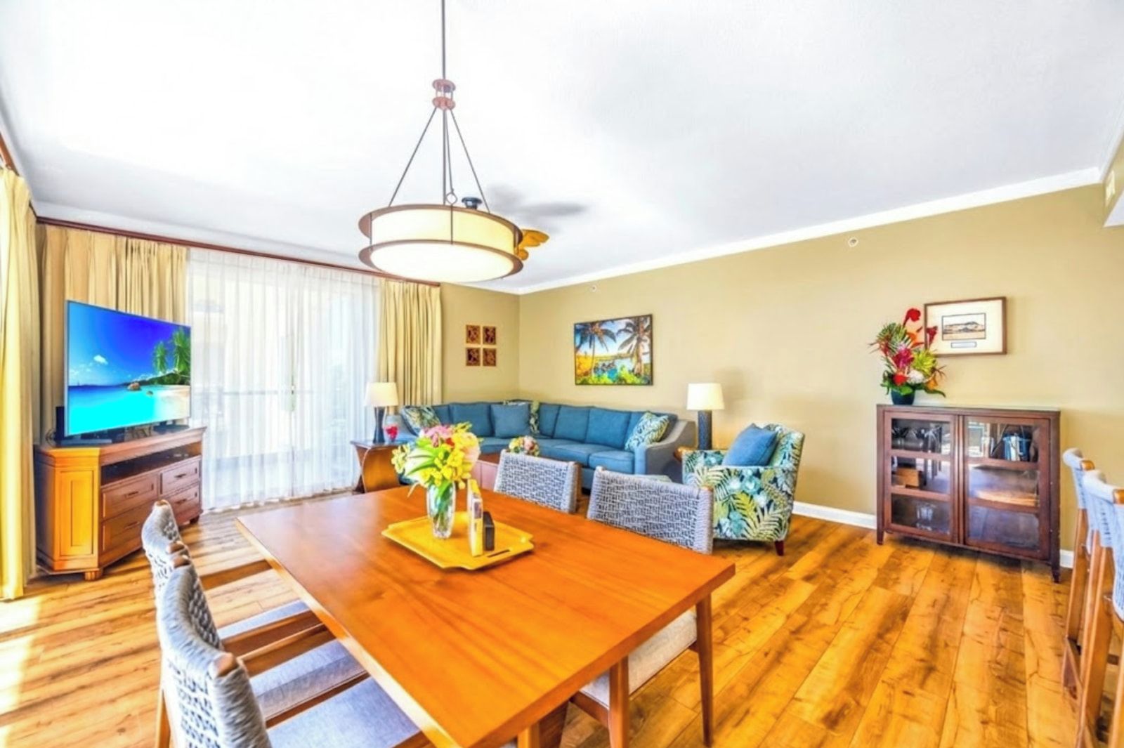 A living room with a wooden dining table, blue sofa, and a television.