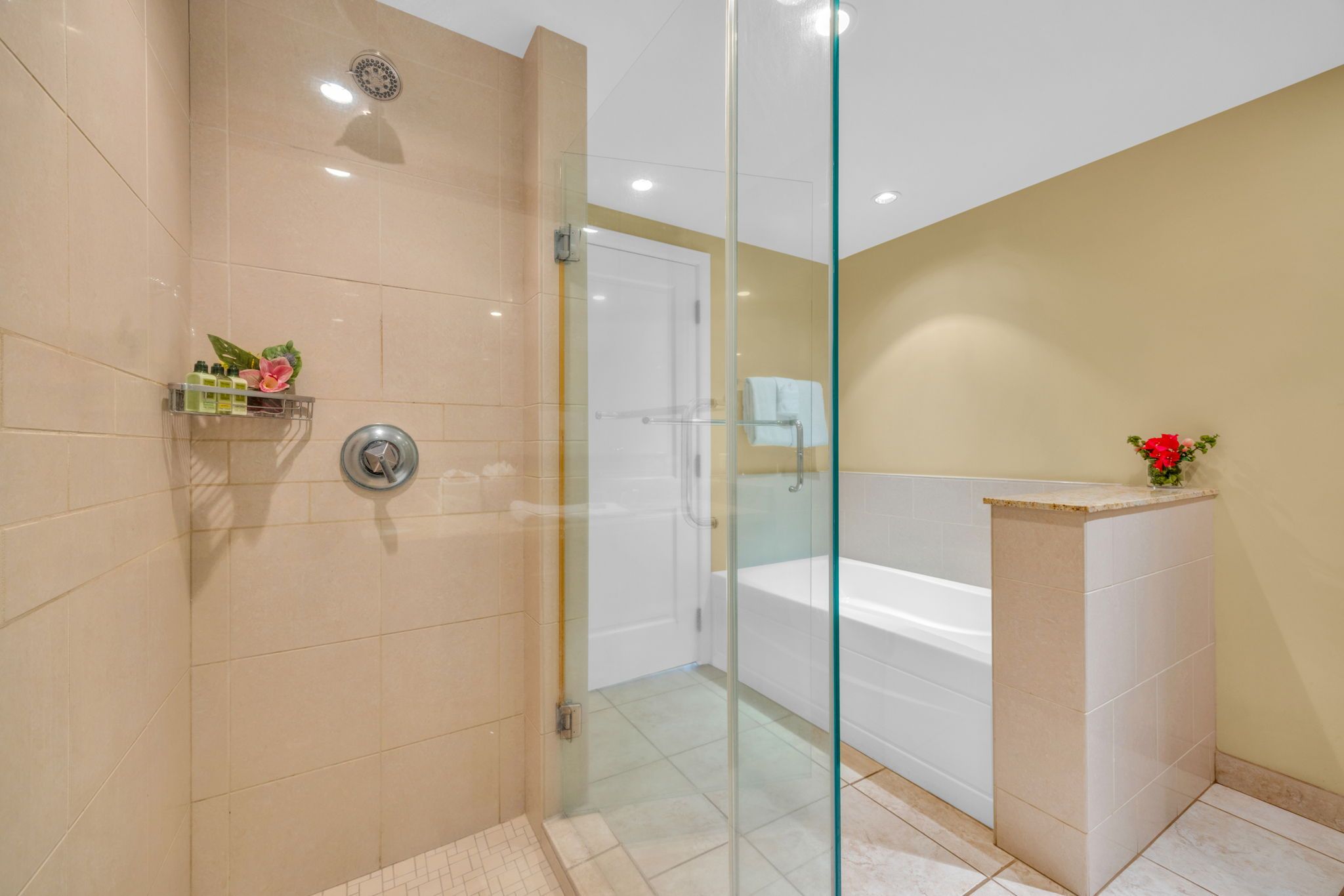 Un bagno moderno con cabina doccia in vetro, una vasca da bagno bianca e un pavimento piastrellato color beige.