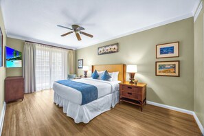 A hotel room with a bed, a nightstand, a ceiling fan, a TV, and artwork on the walls. - Honua Kai | Ocean View 9 BR, Sleeps 28 | Car Incl. w/ 6+ Nights | HKK ML-3374 by KBM (Lahaina)