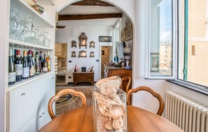 Ein Essbereich mit einem Holztisch, Stühlen, einer Glasvitrine mit Meeresschalen und einem Weinkühlschrank mit Flaschen.