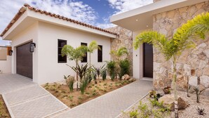 A modern house with a stone facade, a tiled roof, and a paved driveway. - New 4BR Ocean View Villa with Airport Transport (Cabo San Lucas)