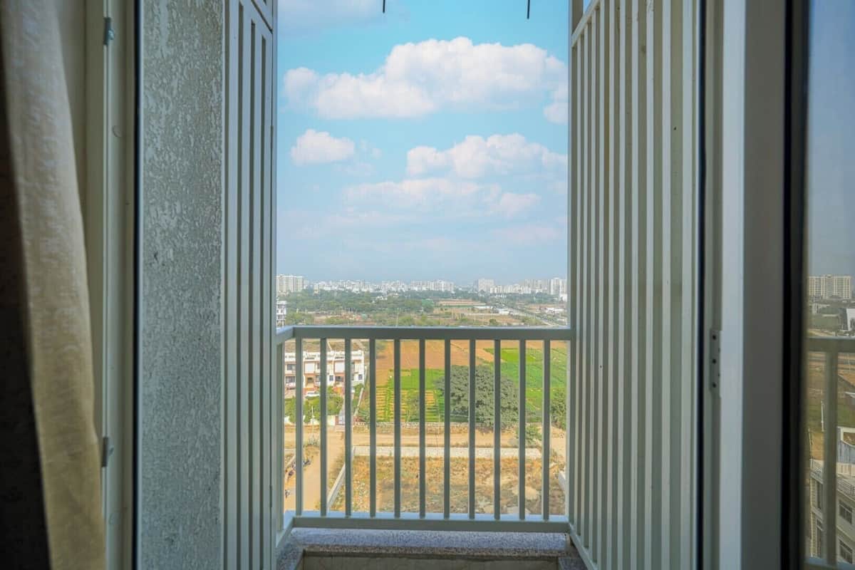 A view from a balcony with a railing, a clear sky, and distant buildings.