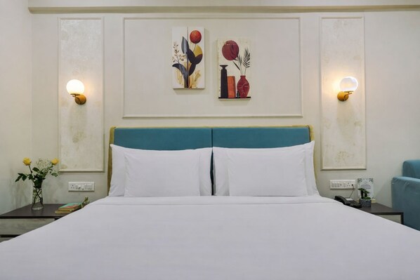 Habitación de hotel con una cama, dos lámparas de pared y dos cuadros en la pared.