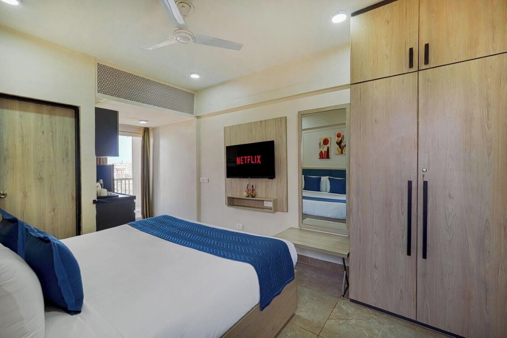Een slaapkamer met een bed, een tv aan de muur, een kledingkast en een plafondventilator.