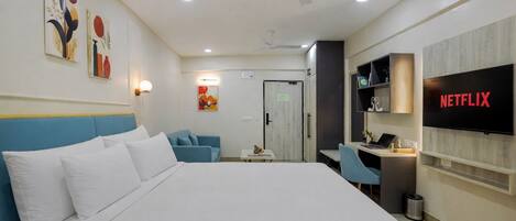 Ein Hotelzimmer mit Bett, Schreibtisch, Stuhl, Fernseher und Bildern an den Wänden.