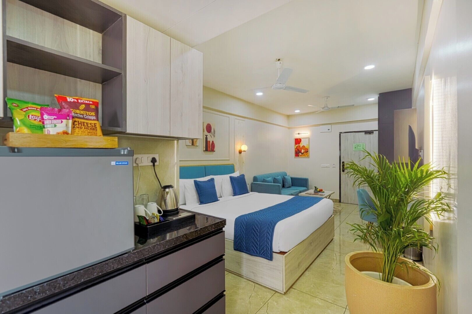 A hotel room with a bed, a kitchenette, a dining area, and a bathroom.