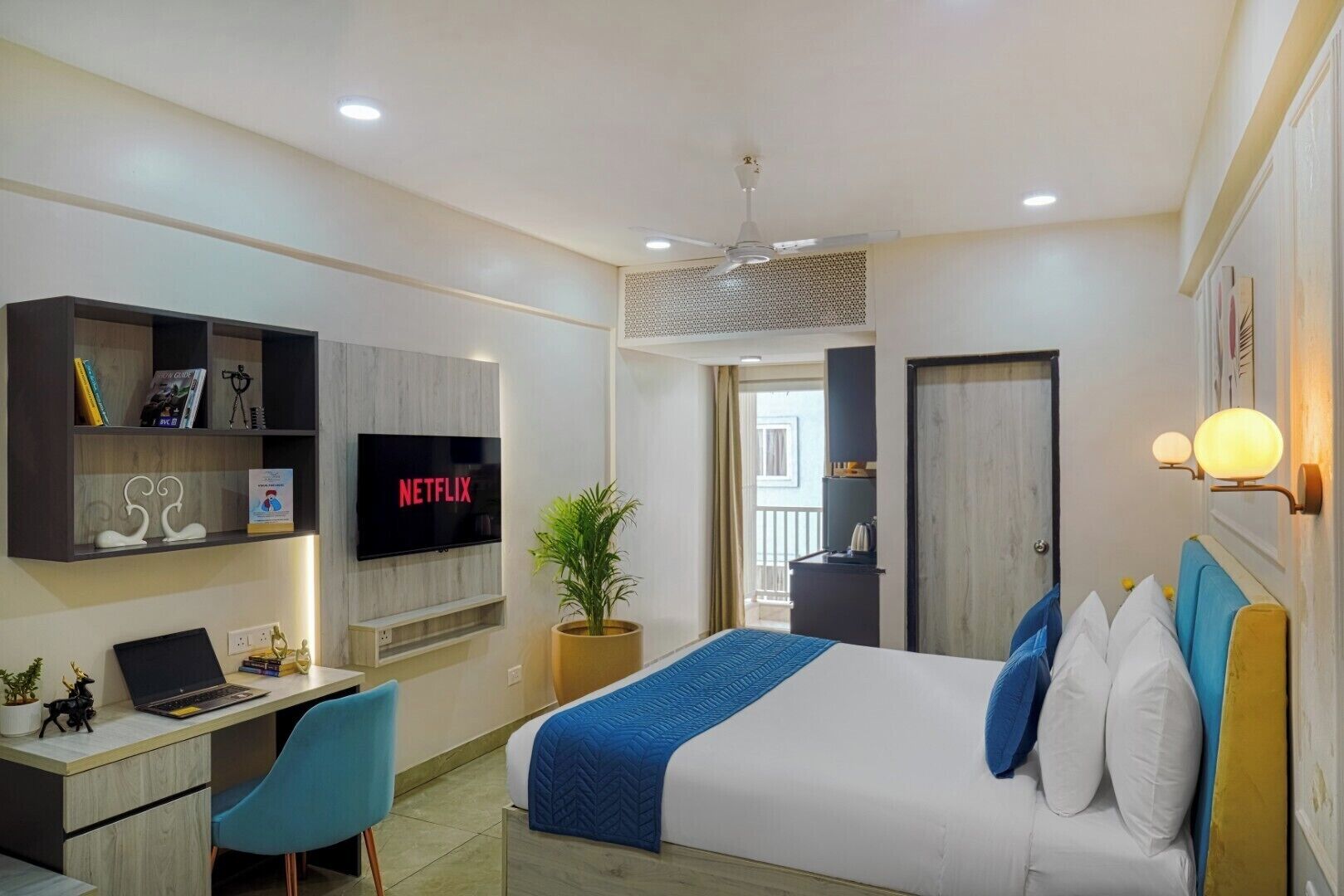 A modern bedroom with a bed, desk, and TV.