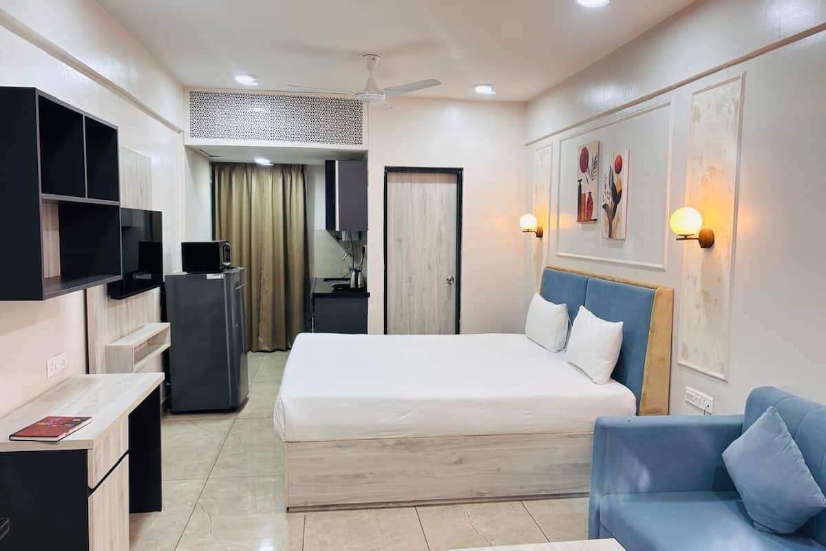 A hotel room with a bed, a desk, a chair, a TV, a microwave, and a wardrobe.