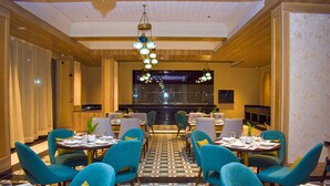 Un comedor de hotel con mesas redondas, sillas color turquesa y piso estampado.